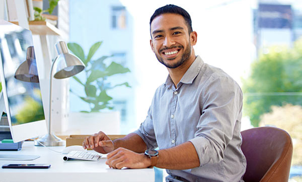 Smiling male AgeSMART team member at desk representing senior home maintenance coordination for aging at home