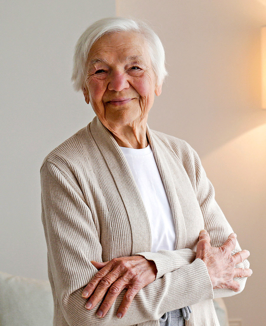 Smiling senior woman standing confidently at home representing the everyday challenges seniors face when seeking reliable in-home support