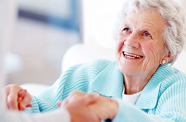 Smiling senior woman receiving supportive in-home personal care assistance at home